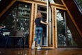 Woman enters forest cabin, back view