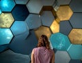 Back view of woman facing large colorful abstract hexagon pattern wall Royalty Free Stock Photo