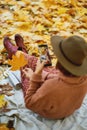 Back view of woman in hat taking photo on camera phone while relaxing in autumn park Royalty Free Stock Photo