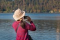 Back view of woman holding mobile phone in hands and taking photo