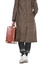 Back view of woman in plaid coat holding vintage weathered suitcase isolated on white. Royalty Free Stock Photo
