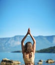 Back view woman practices yoga at nature with beutiful mountains