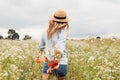 Back view of woman running in blooming field with bouquet of poppies and daisies. Harmony with nature