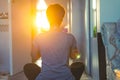 Back view woman sitting on a mat while doing yoga position Namaste mudra during sunset golden hour in the bedroom Royalty Free Stock Photo