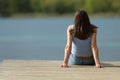 Back view of a woman sitting in a pier contemplating lake Royalty Free Stock Photo