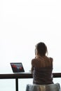 Back view of woman sitting at table and using laptop Royalty Free Stock Photo