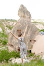 Back view woman standing with raised hands in Cappadocia, ancient cave town in background, Turkey. Royalty Free Stock Photo