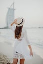 Back view of woman in straw hat walking on sandy beach eanjoying sea view Royalty Free Stock Photo