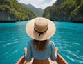 A woman in a swimsuit and hat sits on the bow of a boat in the t