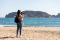 Back view of woman taking pictures with DSLR camera of islands from the beach - Medes Islands Royalty Free Stock Photo