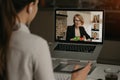 Back view of a woman talking to her colleagues in a video conference on laptop