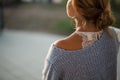 Back view of a woman in blue knitted sweater with tied blond hair looking at the sunset. Royalty Free Stock Photo