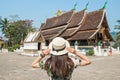 Back view of woman tourist visiting Wat Xieng Thong an iconic temple in Luang Prabang, the UNESCO world heritage town in north cen