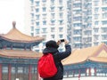 Back view woman toutist taking photograph from smartphone over Chinese building blur background Royalty Free Stock Photo