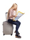 Back view of woman traveler sitting on their suitcases and looking for a route map Royalty Free Stock Photo