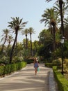 Back view of a woman walking on a path in Villa Bonanno park in Palermo, Italy