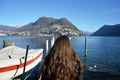 Back view of woman walking on pier with winter clothes, Lake Lugano, Switzerland, Europe Royalty Free Stock Photo