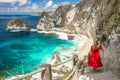 Back view woman wearing a red dress on standing on the stairs leading down at Diamond beach in Nusa Penida, Bali Royalty Free Stock Photo