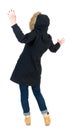 Back view woman in winter jacket Balances waving his arms.