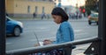 Back view of woman working on laptop sitting on bus stop in city Royalty Free Stock Photo