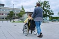 Back view of woman with disabled boy in wheelchair near school building