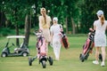 back view of women with golf gear walking on green lawn Royalty Free Stock Photo