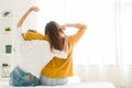 Back view of women lesbian happy couple waking up in morning, sitting on bed, stretching in cozy bedroom, looking through window. Royalty Free Stock Photo