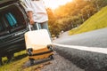 Back view of yellow suitcase dragging baggage suitcase alone road trip for loading into SUV car. People lifestyles and vacation