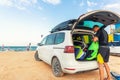 Back view young adult male surfer in wetsuit put out surf board kite equipment on sand beach from van vehicle with Royalty Free Stock Photo