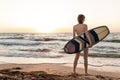 Back view young adult slim sporty female surfer girl with surfboard silhouette stand at ocean coast wave against warm Royalty Free Stock Photo