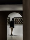 Back view of young asian man standing interested in photograph displayed on white wall at art gallery exhibition hall Royalty Free Stock Photo