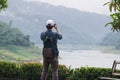 Back view of young Asian traveler man taking photo with mobile smart phone outdoors scenic background. Lifestyle and relaxation co Royalty Free Stock Photo