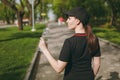 Back view Young athletic beautiful brunette girl in black uniform and cap holding bottle, with water during training Royalty Free Stock Photo