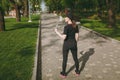 Back view Young athletic beautiful brunette girl in black uniform and cap holding bottle, with water during training Royalty Free Stock Photo