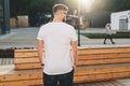 Back view. Young bearded hipster man dressed in white t-shirt and sunglasses is stands on city street. Mock up. Royalty Free Stock Photo