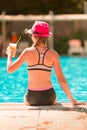 Back view of a young beautiful girl sitting at the pool side Royalty Free Stock Photo