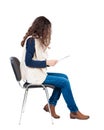 Back view of young beautiful woman sitting on chair. Royalty Free Stock Photo