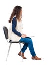 Back view of young beautiful woman sitting on chair. Royalty Free Stock Photo