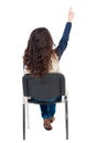 Back view of young beautiful woman sitting on chair and pointin Royalty Free Stock Photo