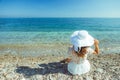 The back view of young beautiful woman in white dress sitting on the beach and looking at the sea horizon Royalty Free Stock Photo