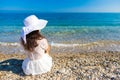 The back view of young beautiful woman in white dress sitting on the beach and looking at the sea Royalty Free Stock Photo