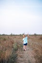 Back view of a young blond girl running happily in an open field