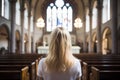 Back view of young blond woman in catholic church