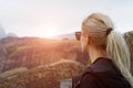 Back view of young blonde girl in mountains at sunset.