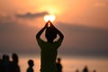 Back view of a young boy silhouette standing and doing Surya Namaskar