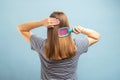 Back view of young brunette woman with hair brush brushing her long healthy hair Royalty Free Stock Photo