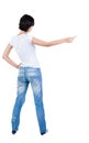 Back view of young brunette woman pointing at wall. beautiful gi