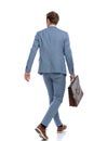 Back view of young businessman in blue suit holding suitcase Royalty Free Stock Photo