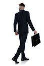 Back view of young businessman holding suitcase and walking Royalty Free Stock Photo