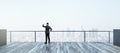 Back view of young businessman looking into the distance on rooftop with bright daylight sky and wide city view. Success, future